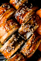 Close-up top view on appetizing Philadelphia sushi rolls with soya sauce and sesame