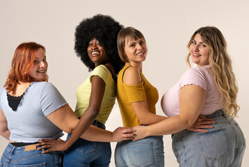 Four diverse and confident women of different nationalities and body types smiling the camera and ...
