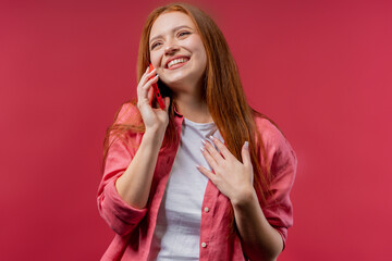 Attractive woman talking by phone, nice joke, smiling. Young lady on pink background. Having smartphone call. - obrazy, fototapety, plakaty