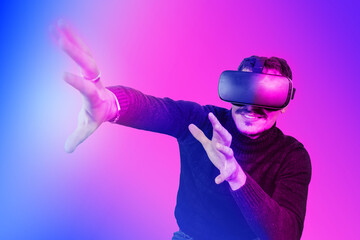 Young man is using virtual reality viewer. Modern man portrait with trendy look and bright colors. - 563139142