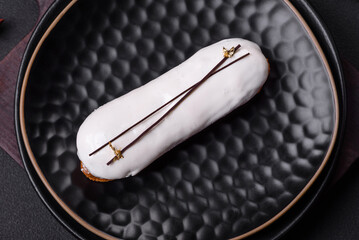 Delicious fresh profiterole or eclair with chocolate on a black ceramic plate