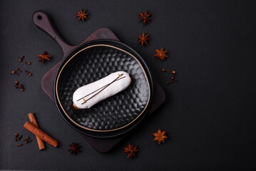 Delicious fresh profiterole or eclair with chocolate on a black ceramic plate