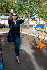 Beautiful amputee woman sitting on swing at park