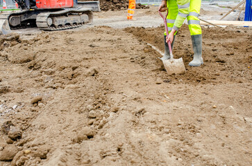 Builder using shovel to clean kerbs and footpath acidentaly covered by top soil