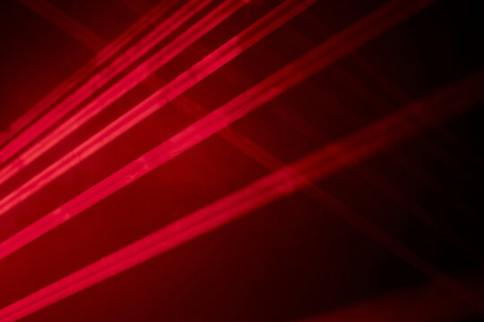 Bright red neon laser lights illuminate the darkness creating lines and triangle shapes in sci-fi effect.
