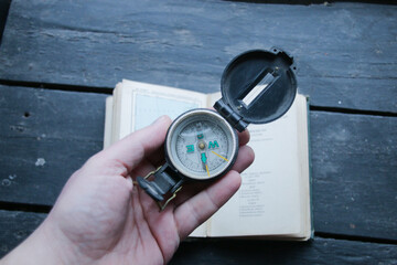 Naklejka premium Hand Holding Navigational Compass on vintage map background