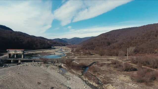 Dried up river bed in a rural countryside with the snowy mountains in the background. Majestic landscape with the rock road and hills.