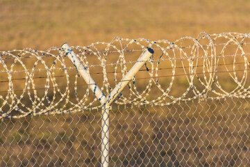 Fence with a roll of barbed wire on top at an international border