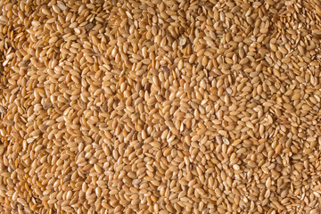 Top view of a close-up of a pile of cleaned golden flax seeds. Organic texture abstract background. Superfood.