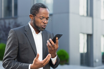 Angry and angry boss talking and shouting on mobile phone, african american businessman in business...