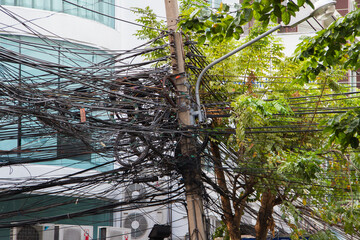 Chaos of cables and wires in Bangkok, Thailand, electric and telephone wires wound on a lamppost