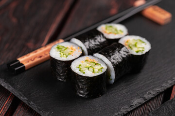 Maki sushi roll with cucumber and sesame with chopsticks close-up. Sushi menu. Japanese food.