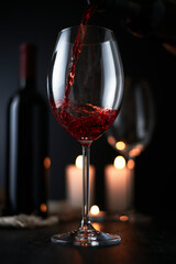 Pouring red wine into wine glass on dark background, still life background