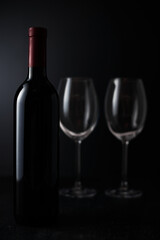 Glasses and bottle of wine on dark background