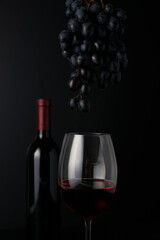 Pouring red wine into wine glass on dark background, still life background