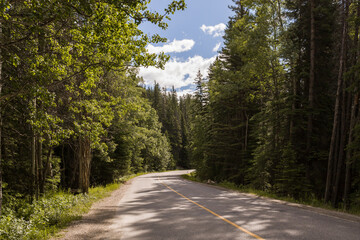 Obraz premium Mountain road. Travel background. Highway in mountains. Transportation. Landscape with rocks, sunny sky with clouds and beautiful asphalt road in the evening in summer. 