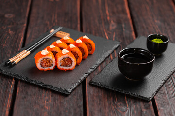 Sushi roll with tuna, onion in batter and tobiko caviar served on black board close-up - Japanese food