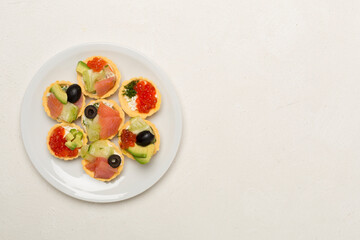 Tartlets with salmon and caviar on concrete background, top view