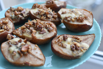 Selective focus of pears baked and roasted with blue cheese, walnuts and  honey on blue plate background. Top view.