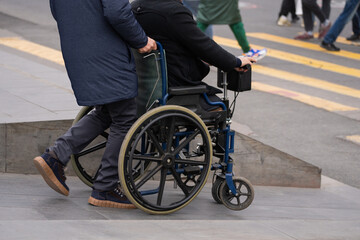 Obraz premium The guy carries a man in a wheelchair