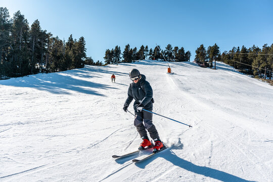 Two boys skiing down a large ski slope.
