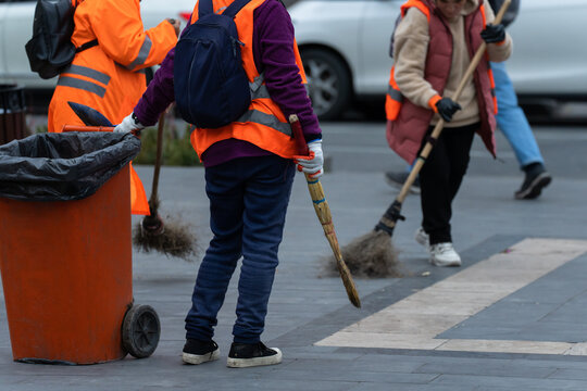 City cleaner dragging a trash can