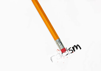 Close up of a yellow pencil erasing racism word on white paper