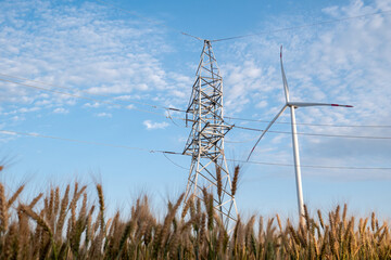 Power transmission lines work from windmill clean energy. Wind turbine produces renewable energy for supporting electricity substation © SlavaStock