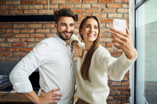 Two people at office taking selfie with phone