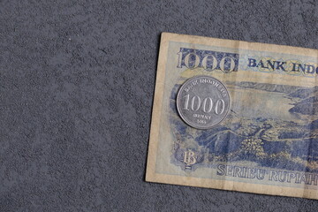 old banknotes and new coin of 1000 rupiah on dark background