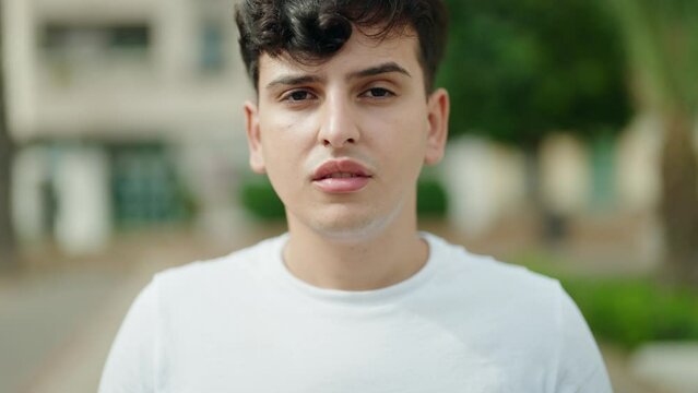 Non binary man standing with serious expression at park