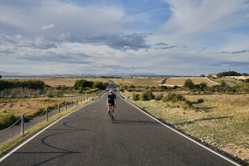 fit young female cyclist riding on the road on a gravel bike at sunset.Empty city road.
Sports motivation.Murcia region in Spain