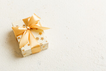 Obraz na płótnie Canvas wrapped Christmas or other holiday handmade present in white paper with gold ribbon on colored background. Present box, decoration of gift on colored table, top view with copy space