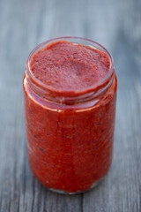 Traditional turkish chili pepper and tomato paste in bowl or spoon with dried peppers and fresh tomatoes on table