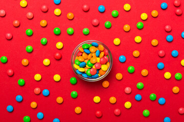 Multicolored candies in a bowl on a colored background. birthday and holiday concept. Top view with copy space
