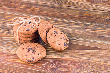 View of oatmeal cookies with chocolate on wooden table, close-up, selective focus. Homemade cookies on old wooden table
