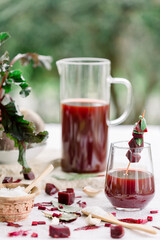  Beet kvass in a glass and mason jar with loose beets, side view, gray background