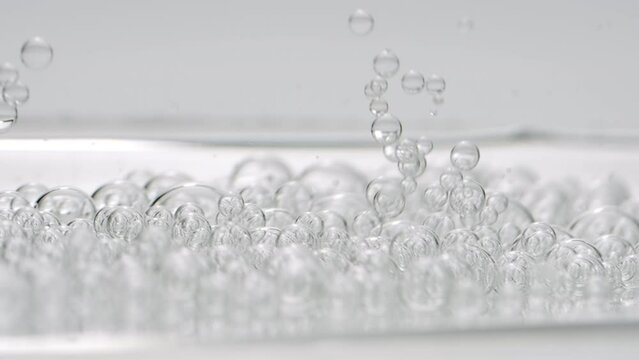 Macro shot of grey clear bubbles sink to another ones on grey background | Abstract body care cosmetics with hyaluronic acid formulation concept
