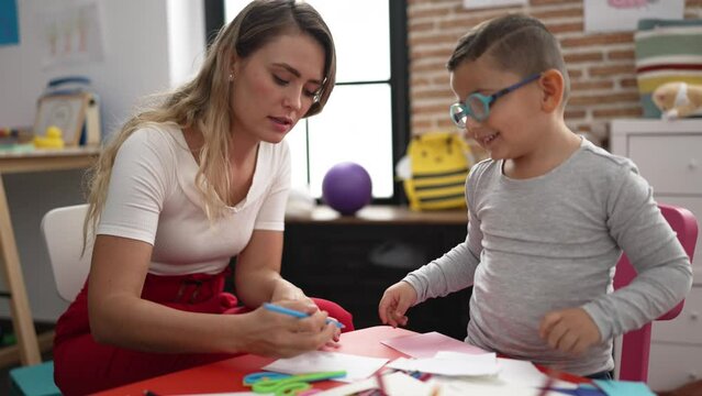 Teacher and toddler sitting on table having handcrafts class at kindergarten