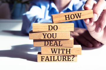 Close up on businessman holding a wooden block with "How Do You Deal With Failure?" message