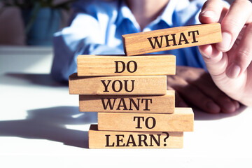 Close up on businessman holding a wooden block with "What Do You Want To Learn?" message