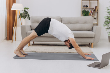 Handsome bearded man doing hamstring stretch exercise at home.