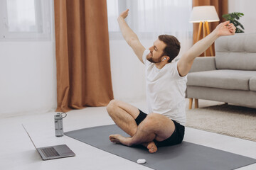 Fototapeta na wymiar Keep calm on quarantine. Millennial guy meditating with trainer online via laptop connection, empty space