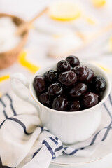 Various olives flavored with spices in white cup and glass jar. Green olives, black olives. Front and top shot on a white background	
