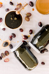 Obraz na płótnie Canvas Jar of grape molasses, grape syrup. Sweetener, cough medicine. Black, green and purple grapes on kitchen table.