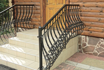 threshold of gray concrete steps with black forged iron handrails on the street near the wooden...