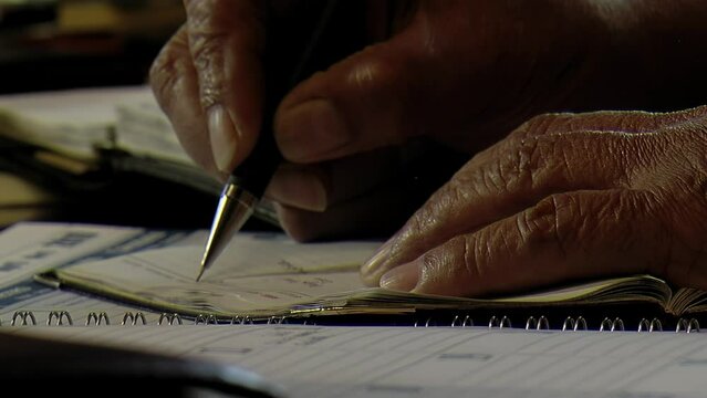 Hands of An Elderly Man Writing on A Piece of Paper at Home. Close up.