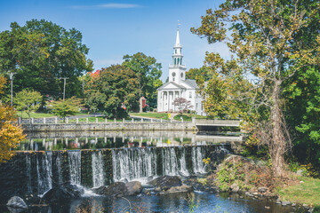 Milford, town in Connecticut. View of white church and waterfall surrounded by trees - obrazy, fototapety, plakaty