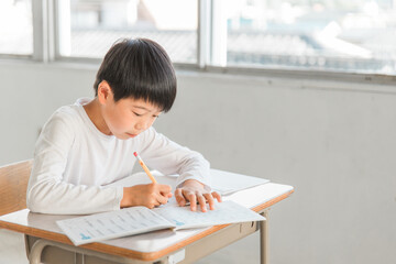 学校の国語の授業で漢字の書き取りをする小学生の男の子
