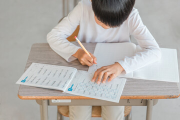 学校の国語の授業で漢字の書き取りをする小学生の男の子
